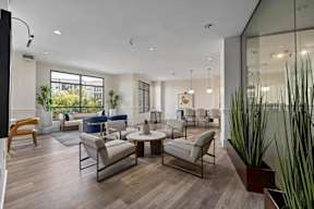 A modern living room with a glass wall and a large window.