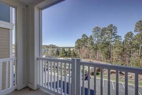 A balcony with a view of a road and trees.