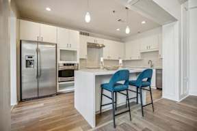 A kitchen with a white island and blue chairs.