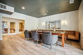 A modern dining room with a long table and grey chairs.