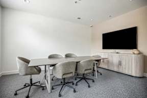 A conference room with a table, chairs, and a television.