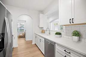 A kitchen with white cabinets and a stainless steel dishwasher.