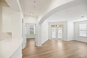 A white interior with a wooden floor and a white door.