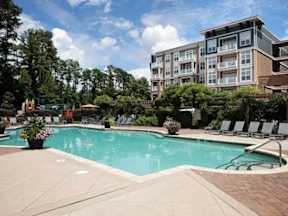 A swimming pool surrounded by lounge chairs and trees.