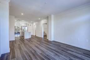 A spacious room with wood flooring and white walls.