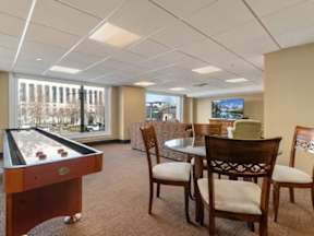 A room with a pool table, chairs, and a television.