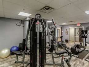 A gym with a variety of equipment including a treadmill, a stationary bike, and a leg press machine.