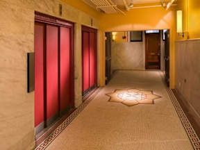 A hallway with red doors and a light on the floor.