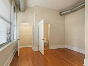 A room with wood floors and a toilet in the corner.