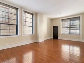 A room with wooden floors and two windows.