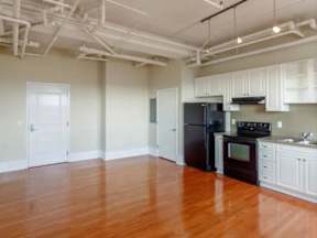 A kitchen with white cabinets and a black fridge.