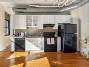 A kitchen with black appliances and white cabinets.