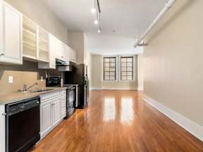 A kitchen with black appliances and wooden floors.