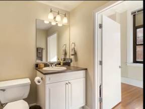 A bathroom with a white toilet and a white sink with a brown counter.