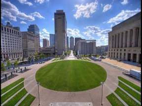 A city park with a grassy area and buildings in the background.