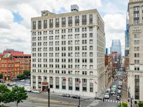 A street view of a city with a large white building in the middle.