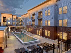 A pool surrounded by patio furniture and a black fence.
