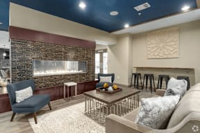 A living room with a stone fireplace and a grey sofa.