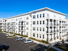 A white apartment building with cars parked in the parking lot.