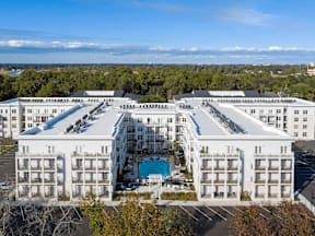 A large white hotel with a pool in the middle of it.