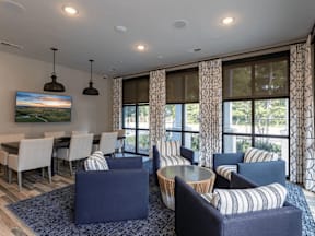 A living room with a large painting on the wall and a dining table with chairs.