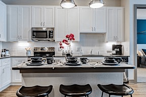 A kitchen with white cabinets and a grey island.