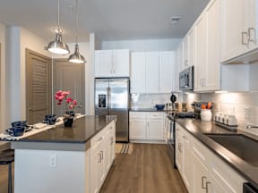 A kitchen with white cabinets and a black countertop.