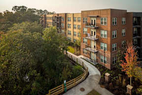 A view of apartment buildings with a walkway and trees in the foreground.