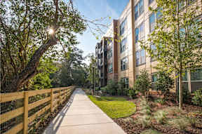 A wooden fence runs along a sidewalk in front of a building.