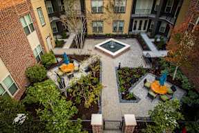 A courtyard with a fountain surrounded by trees and benches.