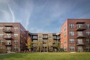 A large apartment complex with multiple balconies and trees in the front yard.