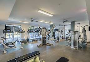 A gym with a variety of equipment including treadmills, weights, and exercise machines.