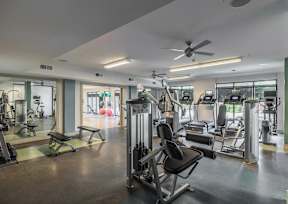 A gym with a variety of equipment including treadmills, weights, and exercise machines.