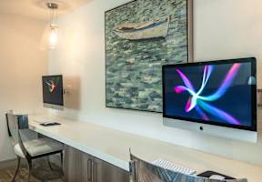 A modern workspace with a large monitor, keyboard, and a painting on the wall.
