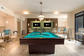 A pool table in a room with a light brown floor.
