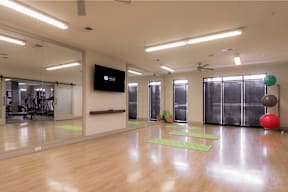 A gym with a mirror, exercise balls, and yoga mats.