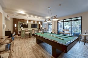 A billiards table is in the middle of a room with a pool table and a television.
