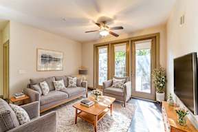 A living room with a grey couch, a coffee table, a television, and a painting on the wall.