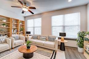 A living room with a white sofa, a wooden coffee table, and a ceiling fan.
