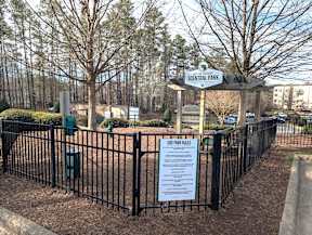 A sign in front of a fence that says Dog Park Rules.