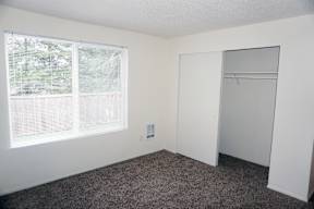 an empty bedroom with a large window and a closet