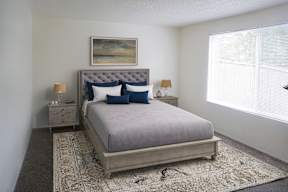 A bedroom with a large bed and a painting above it at Heritage Woods Apartments in Redmond.