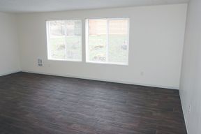 an empty room with wood floors and two windows