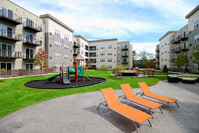 Courtyard with playground and orange lounge chairs at Arden of Oak Brook Apartments, Oakbrook Terrace, IL 60181