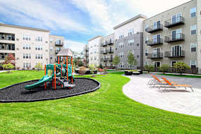 Outdoor playground area with lounge seating and green lawn at Arden of Oak Brook Apartments, Oakbrook Terrace, IL