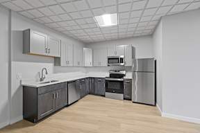 A kitchen with a refrigerator, oven, and sink.