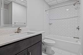 A white toilet sits next to a white bathtub in a bathroom.