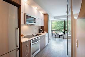 Kitchen with wooden cabinets, black and white appliances at Artline Apartments, Washington-DC