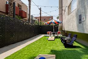 a backyard patio with tables and chairs and grass
