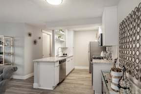 a kitchen with white cabinets and stainless steel appliances and a living room with a couch